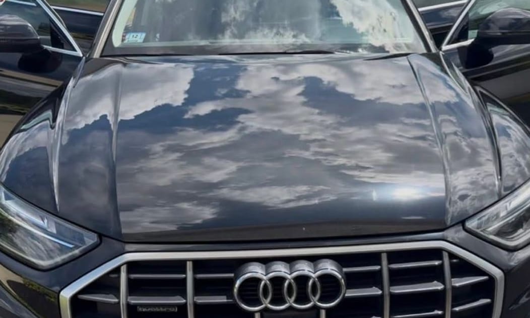 Freshly detailed black Audi hood reflecting the sky